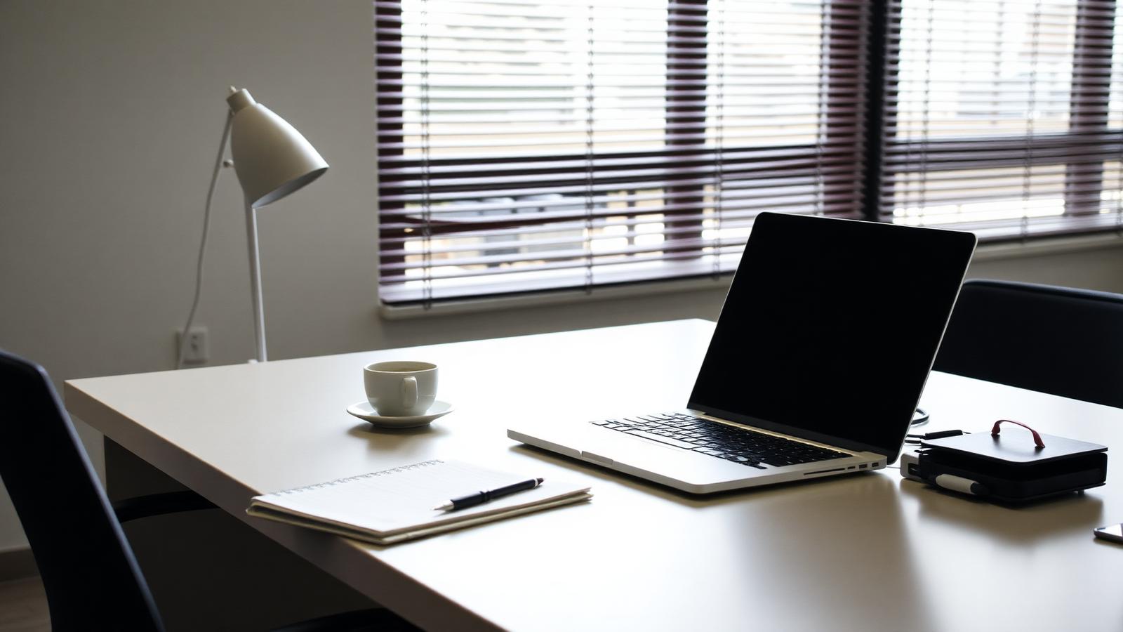 Empty modern office desk with a closed laptop, notebook and coffee cup